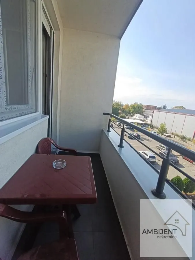 Natkriveni balkon sa stolom, stolicama i pogledom na ulicu.