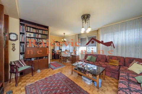 Dnevna soba sa garniturom, velikom bibliotekom i trpezarijom u pozadini. - image 2