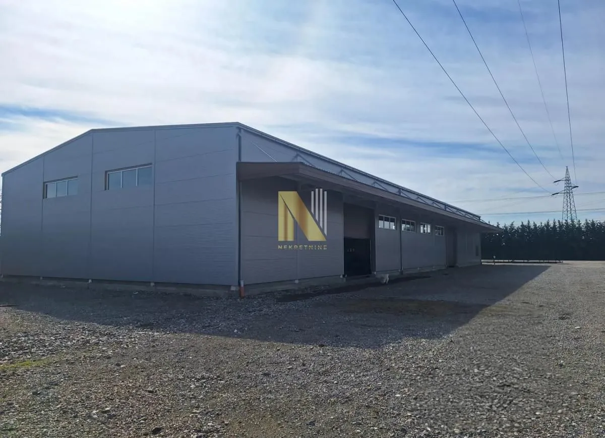 Exterior view of a large warehouse with a gravel driveway.