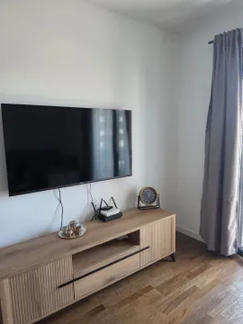 Dnevna soba sa televizorom na zidu i drvenom komodom. - image 9