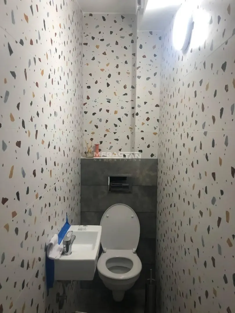 Manje kupatilo sa šarenim pločicama i ugradnom šoljom.