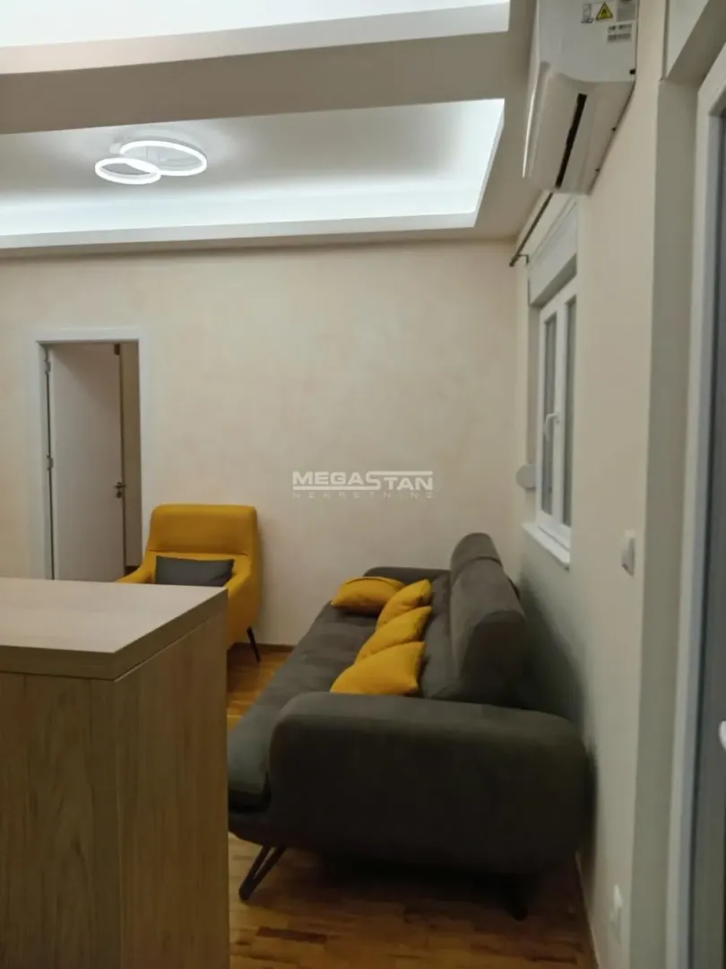 Dnevna soba sa sivom garniturom, žutim jastucima i foteljom.