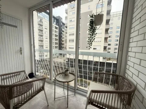 Zastakljeni balkon sa garniturom za sedenje i pogledom na grad. - image 12