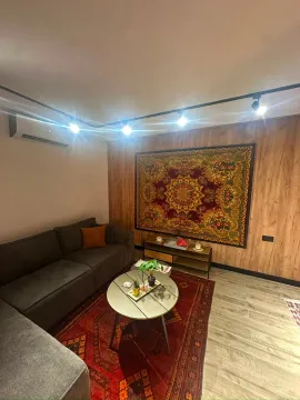 Uređena dnevna soba sa ugaonom garniturom, stočićem i dekorativnim elementima na zidu. - image 5