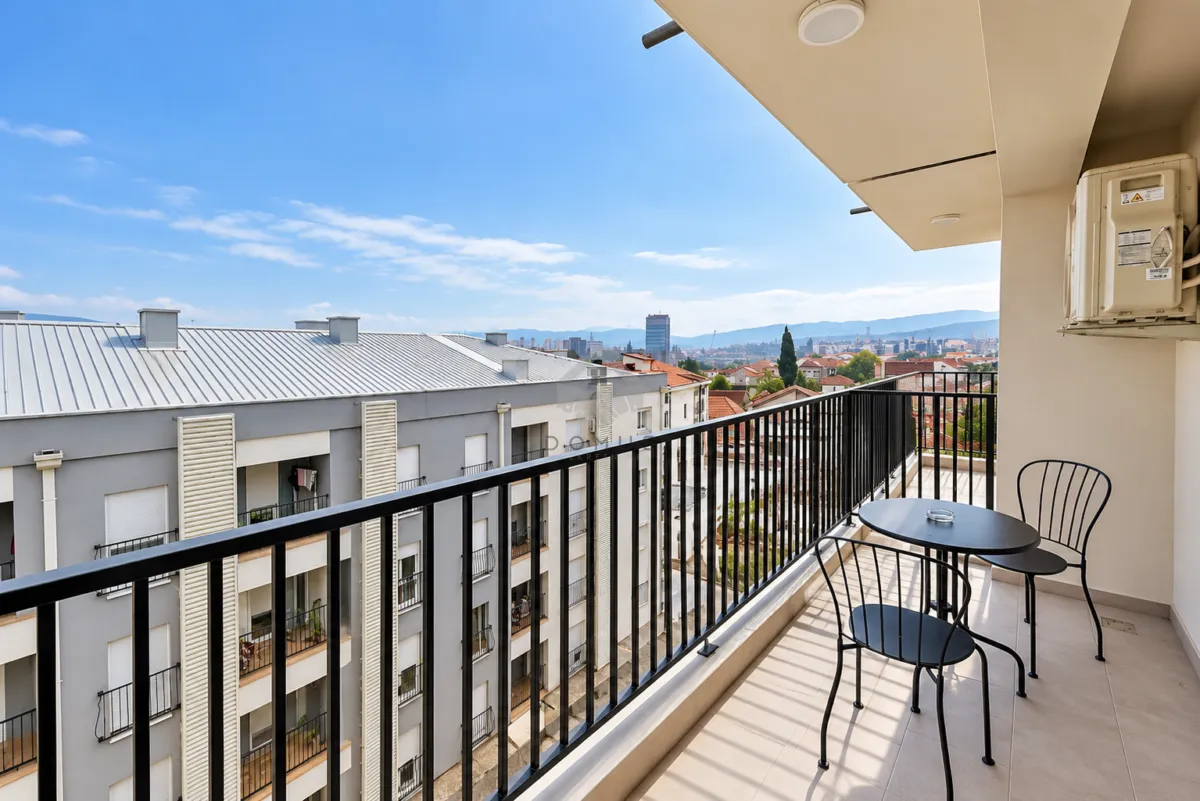 Namtješten balkon sa stolom i dvije stolice i pogledom na grad.