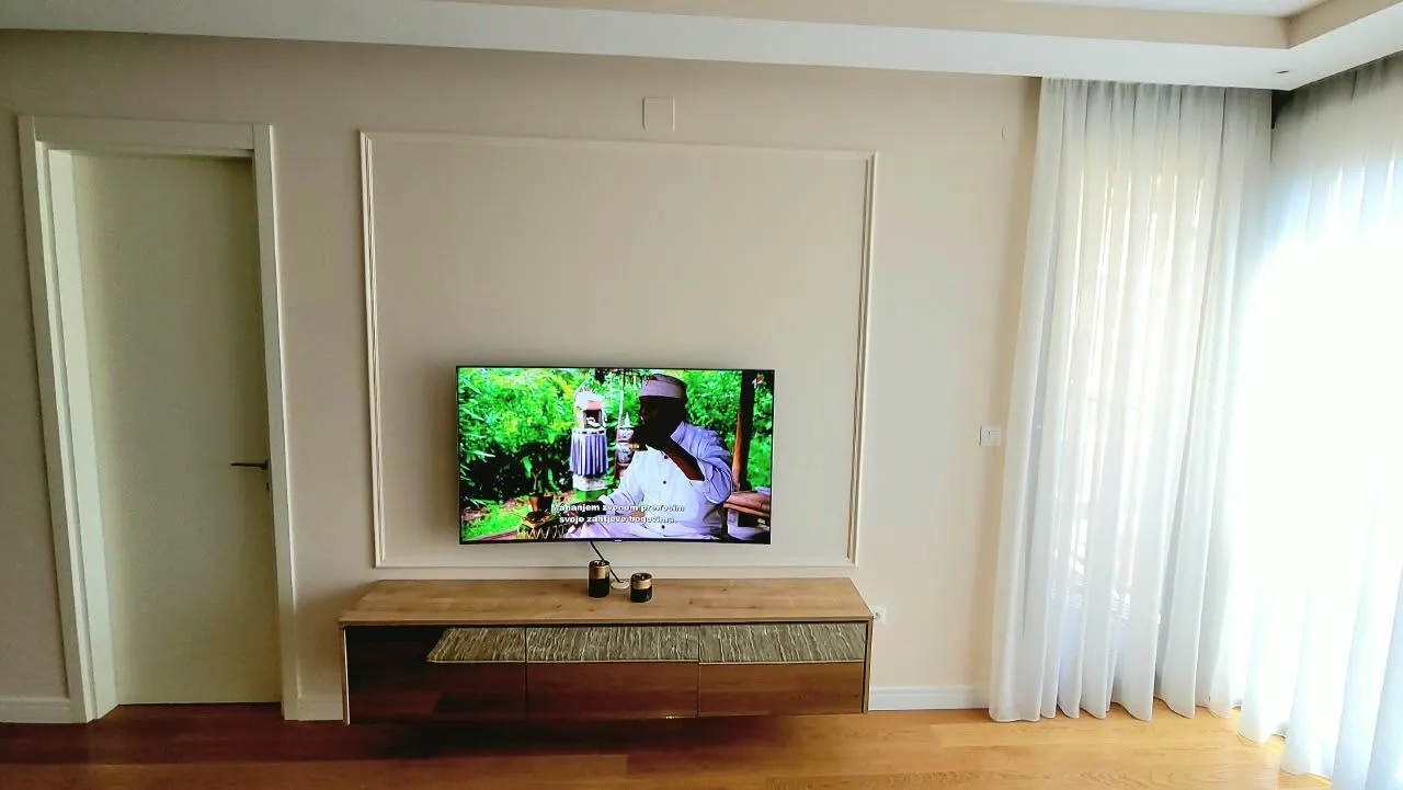 Dnevna soba sa TV komodom i televizorom na zidu.