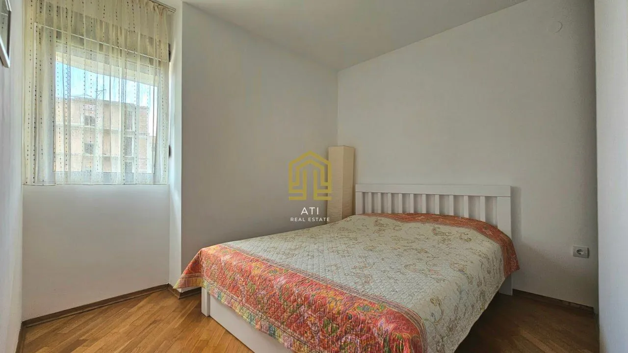 Bright bedroom with a double bed and wooden flooring.