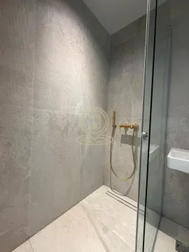 Modern shower cabin with grey tiles and gold-colored faucet. - image 11