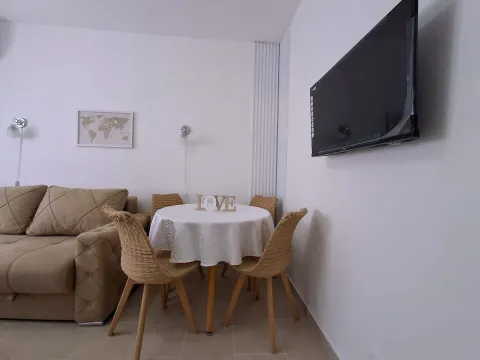 Dnevni boravak sa garniturom, trpezarijskim stolom i televizorom na zidu. - image 4