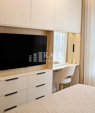 Modern bedroom with built-in wardrobes, a TV panel, and a vanity table. - image 7