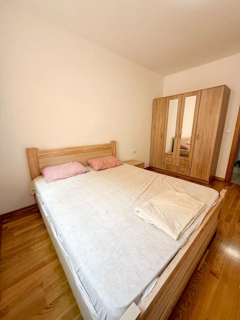 Spavaća soba sa bračnim krevetom i drvenim ormarom.