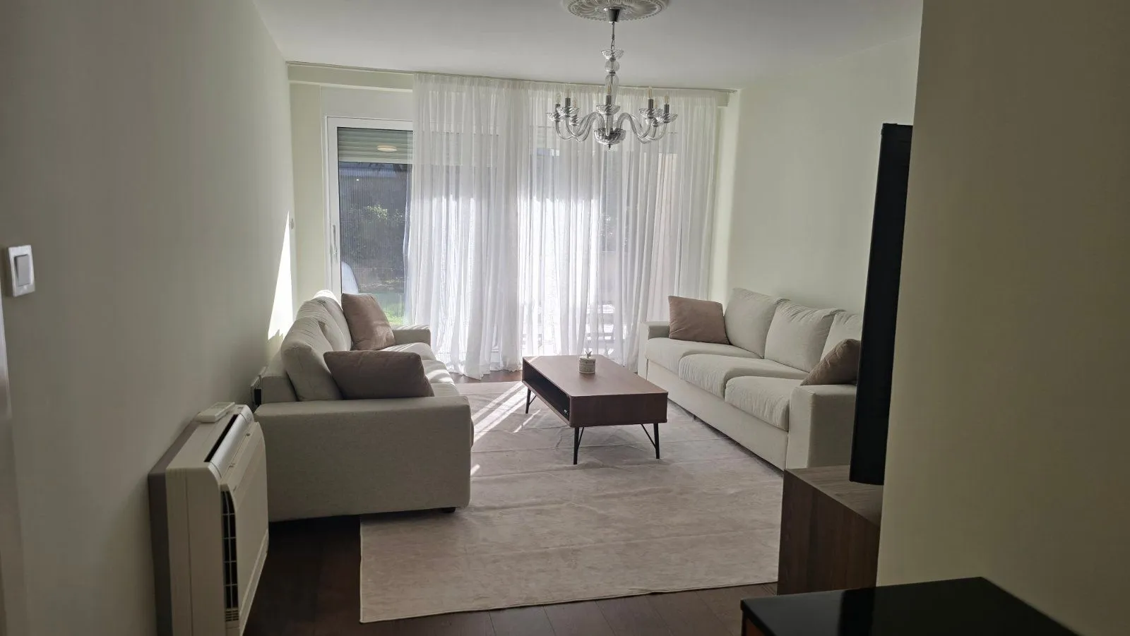 Spacious living room with sofa set and large windows.