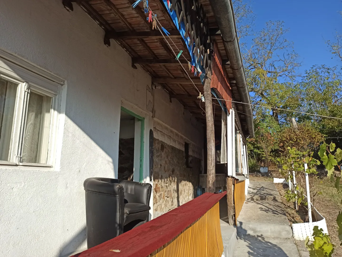 Pogled na spoljašnjost kuće sa natkrivenom terasom i dvorištem.