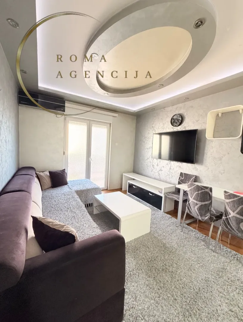 Living room with a sofa, TV, and dining table.