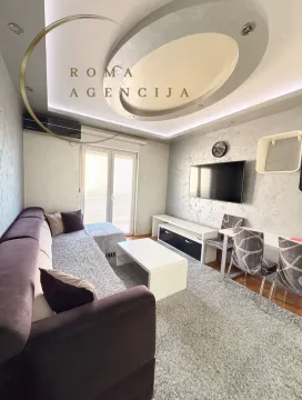 Living room with a sofa, TV, and dining table. - image 2