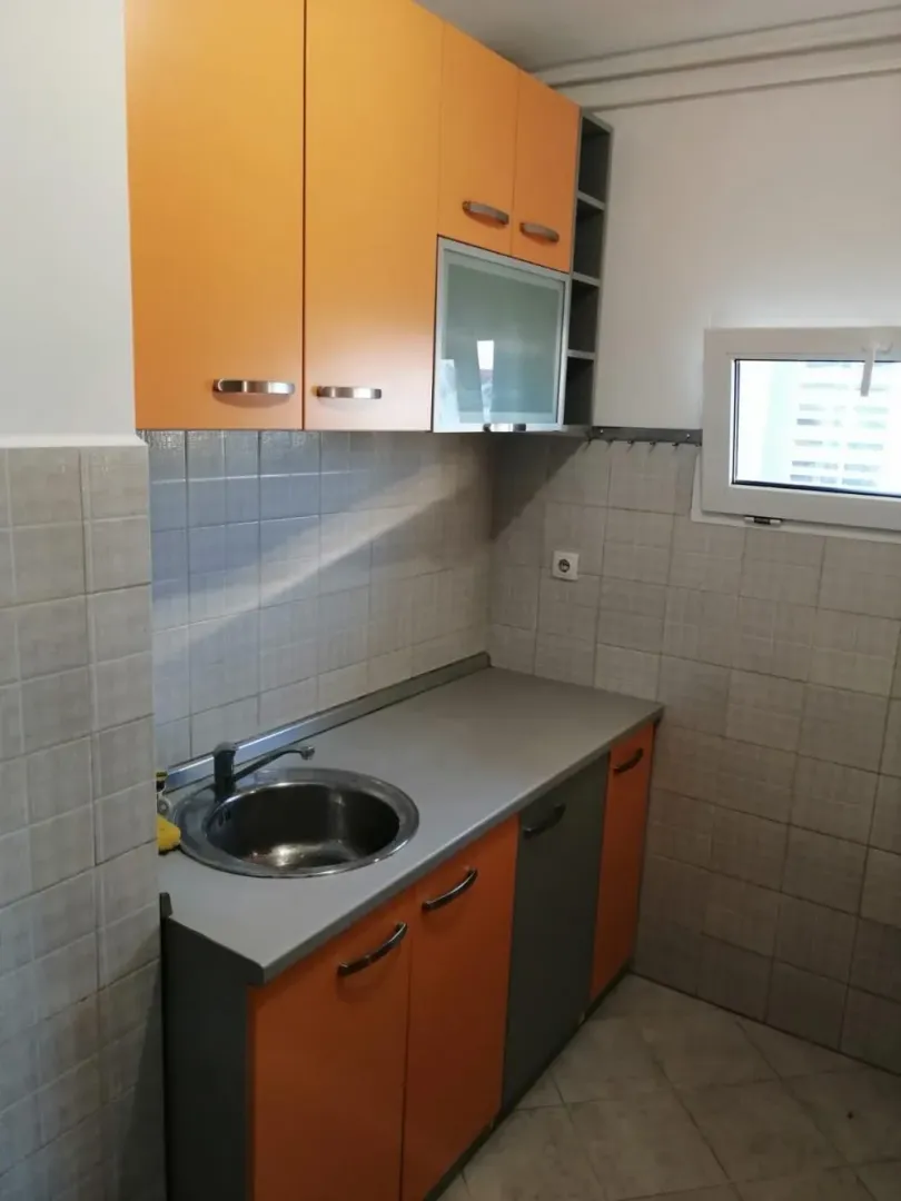 Small kitchen with orange cabinets and a sink.