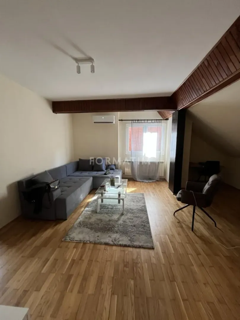 Living room with a sofa, coffee table, and wooden flooring in the attic.