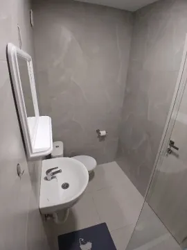 Smaller bathroom with a sink, toilet, and mirror with a shelf. - image 8