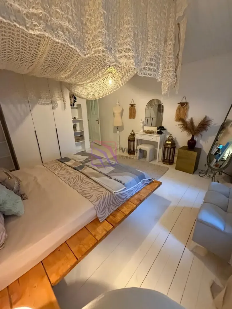 Spacious bedroom with a large bed, white wooden floor, and decorative lighting.