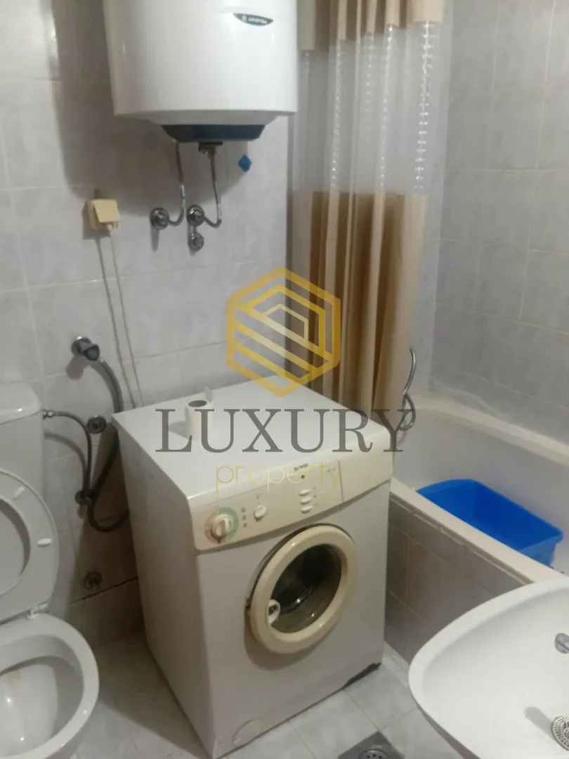 Small equipped bathroom with a bathtub, washing machine, and toilet.