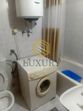 Small equipped bathroom with a bathtub, washing machine, and toilet. - image 5