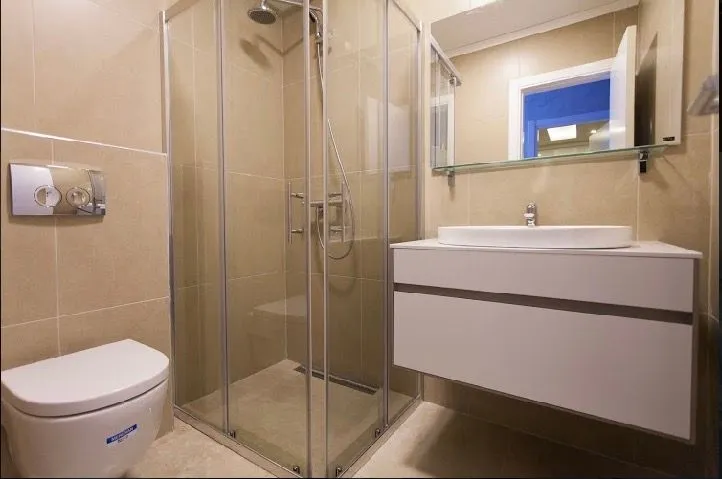 Modernly equipped bathroom with a shower cabin, washbasin, and toilet.