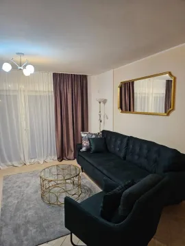 Furnished living room with a black sofa, gold coffee table, and a mirror on the wall. - image 5