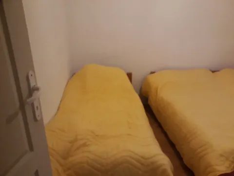 Spavaća soba sa dva kreveta prekrivena žutim pokrivačima. - image 5