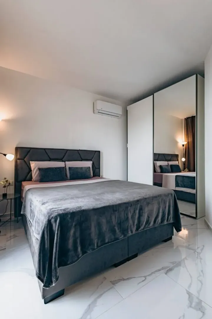 Modern bedroom with a double bed and a large mirrored wardrobe.