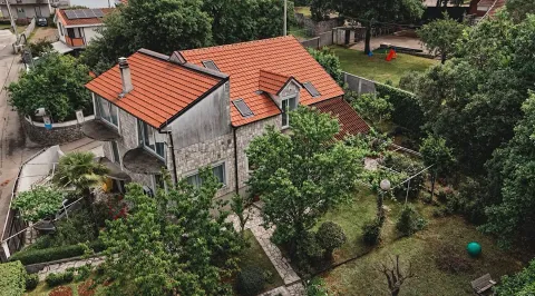 Pogled iz vazduha na kuću sa crvenim krovom i uređenim dvorištem punim zelenila. - image 2