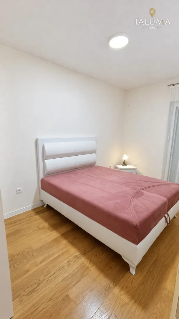 Spavaća soba sa bračnim krevetom i noćnim stočićem.