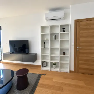 Living room with a TV, white bookshelves, and an air conditioning unit on the wall. - image 4