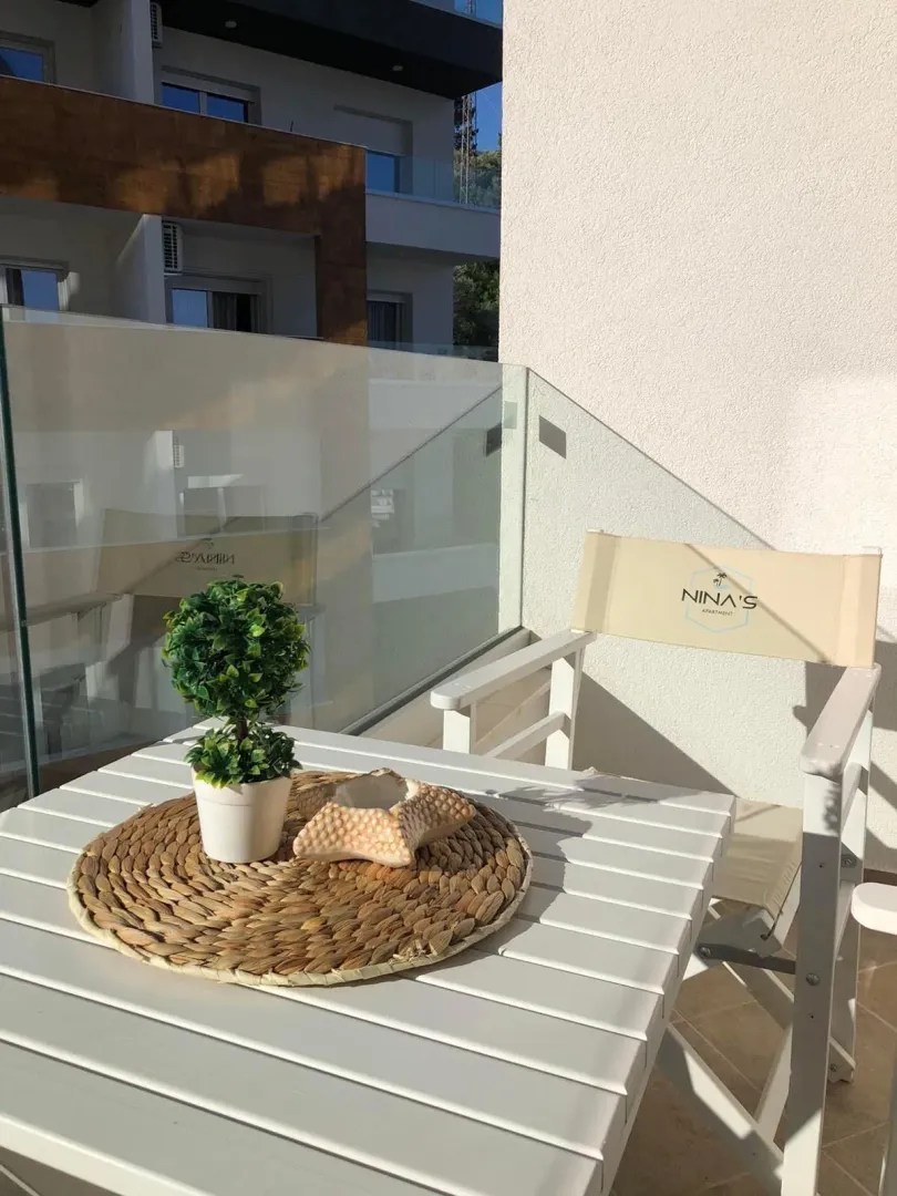 Namješten balkon sa stolom, stolicom i staklenom ogradom.
