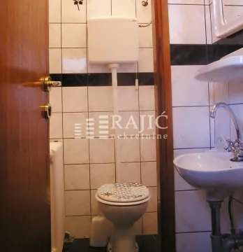 Small bathroom with white tiles, toilet, and sink. - image 2