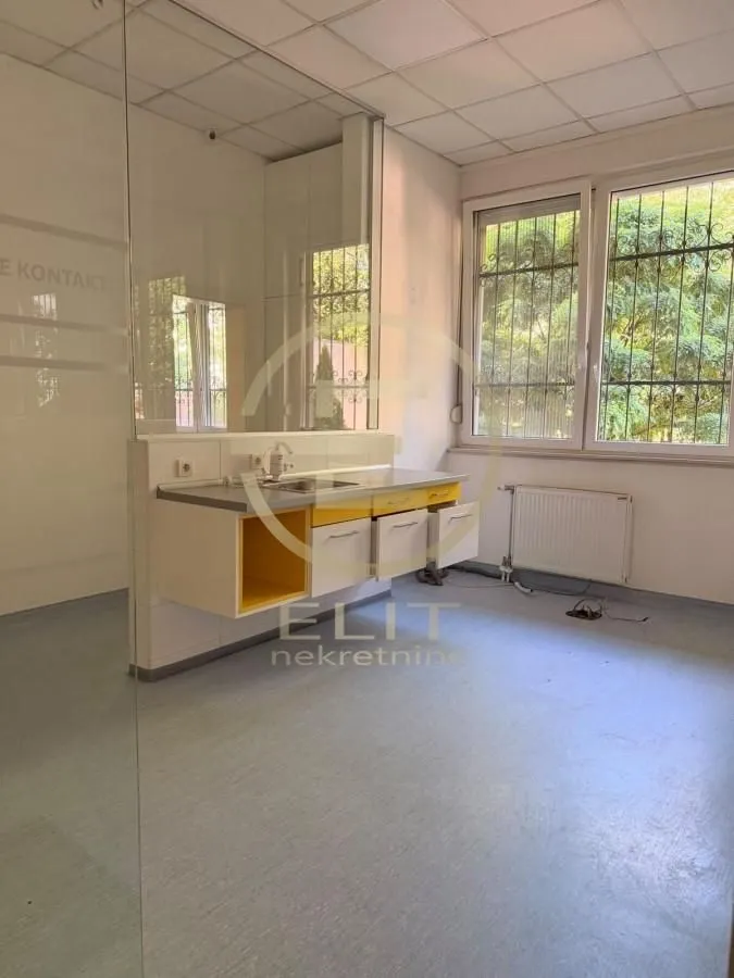 Small kitchen with a sink in an empty room with windows.