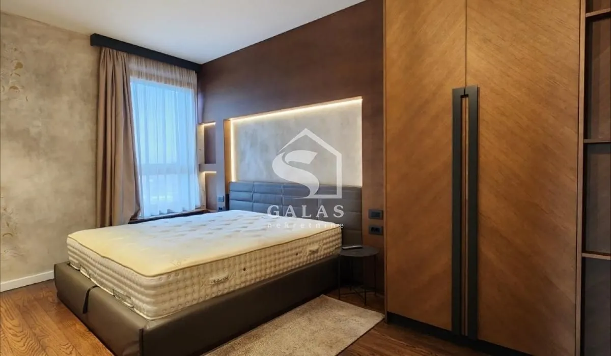 Modern bedroom with a double bed, wooden wall panels, and a wardrobe.