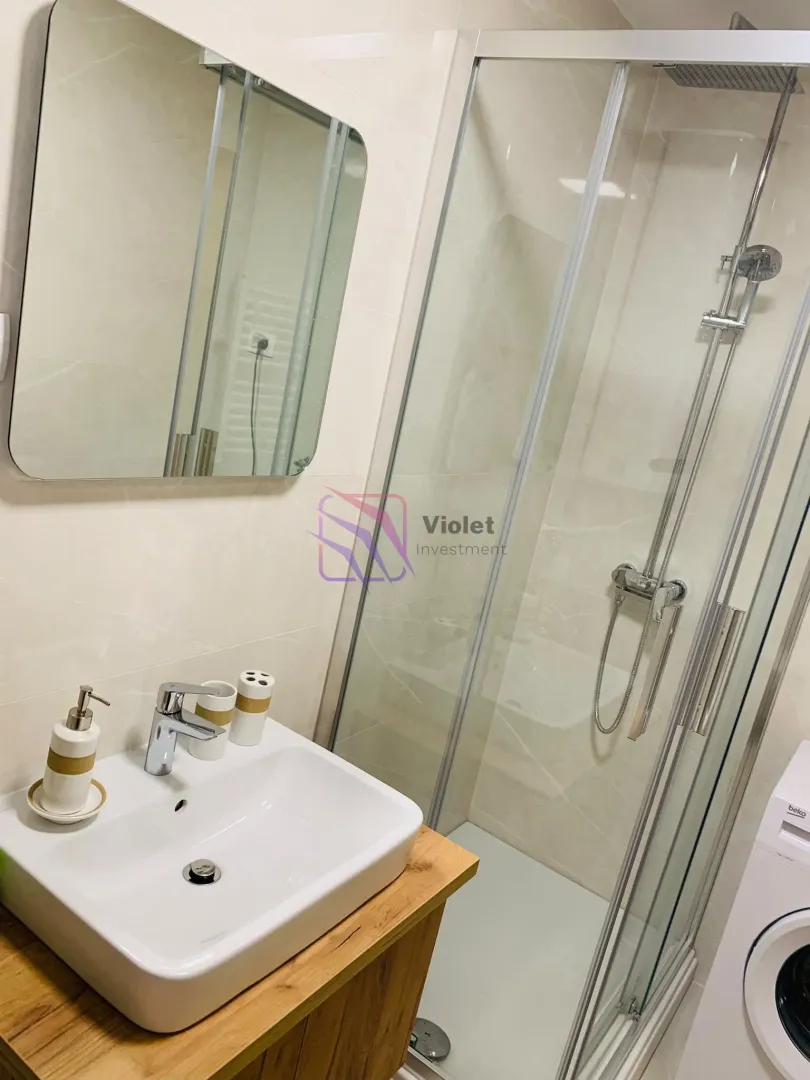 Modern bathroom with a shower cabin, washbasin, and mirror.