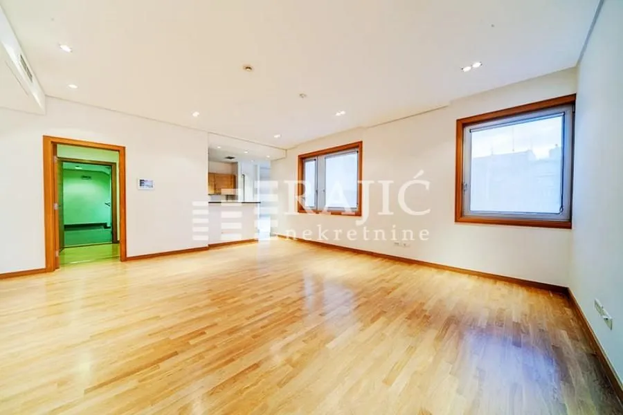 Spacious empty room with hardwood flooring and white walls.