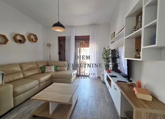 Living room with a sofa, TV unit, and access to the terrace.
