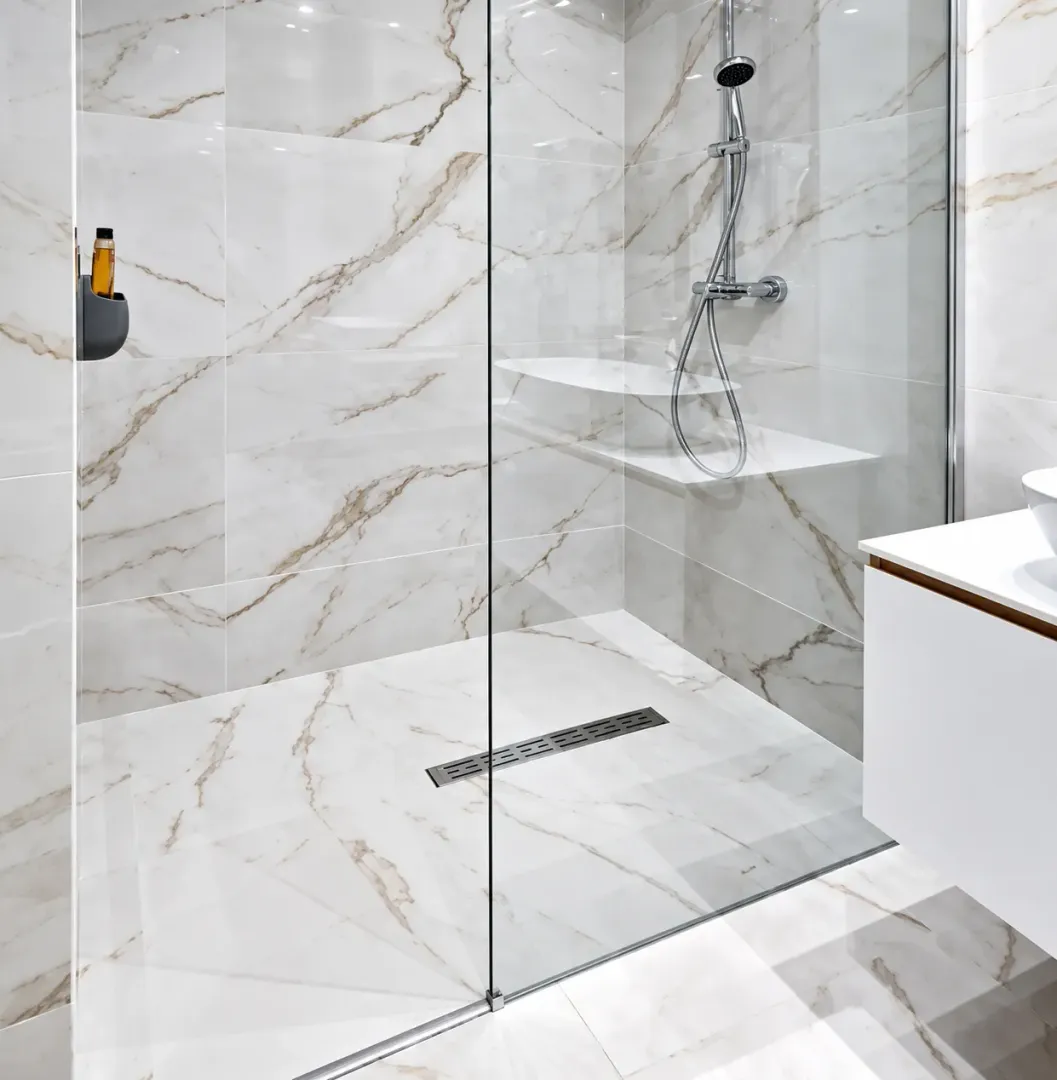 Modern walk-in shower with a glass partition and marble tiles.