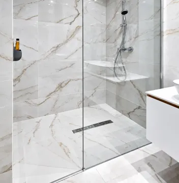 Modern walk-in shower with a glass partition and marble tiles. - image 2