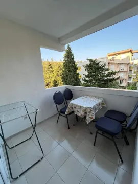 Covered balcony with a table, chairs, and a clothes drying rack. - image 3