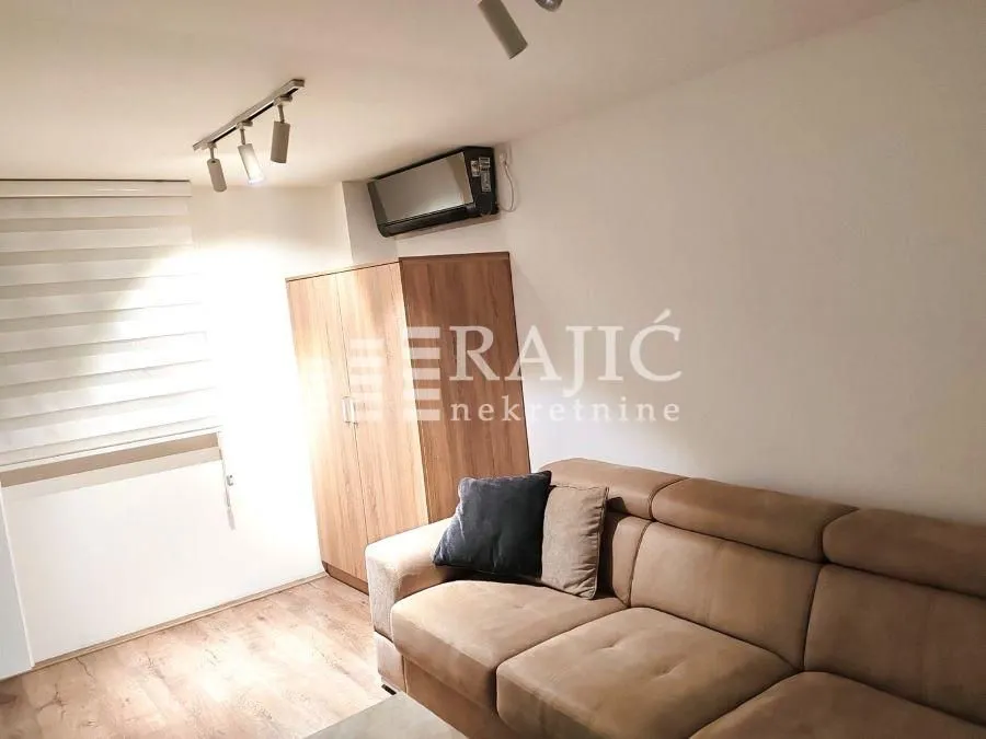 Living room with a sofa, wardrobe, and air conditioning.