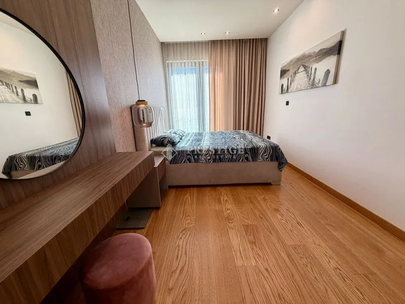 Modern bedroom with a double bed, wooden floor and a mirror.
