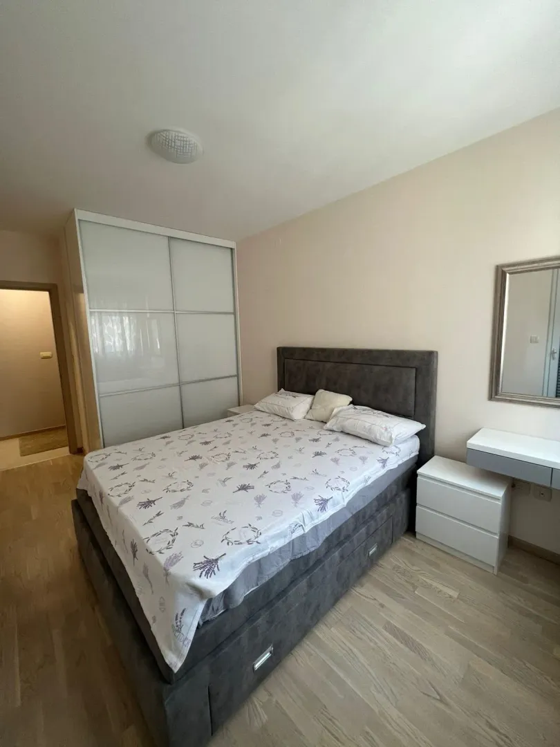 Namještena spavaća soba sa bračnim krevetom, plakarom i komodom.