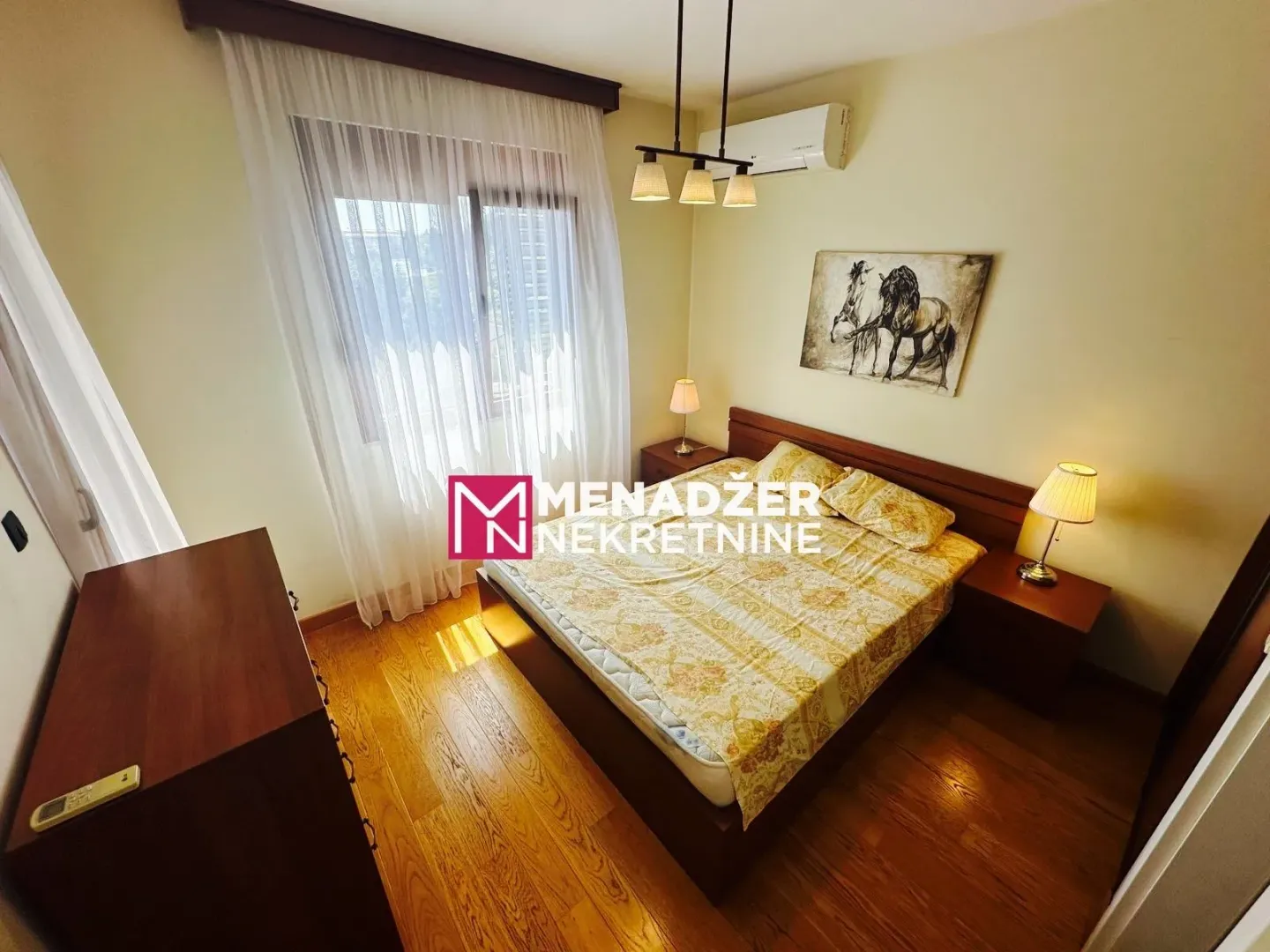 Furnished bedroom with a double bed, bedside cabinets, and a painting on the wall.