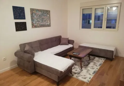 Living room with a sectional sofa, coffee table, and paintings on the wall. - image 4