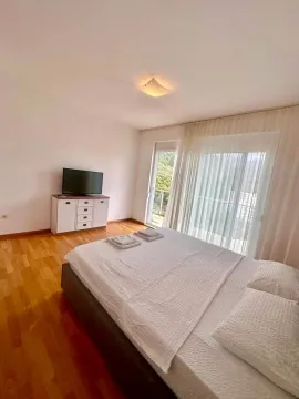 Svijetla spavaća soba sa bračnim krevetom, drvenim podom i izlazom na terasu. - image 4