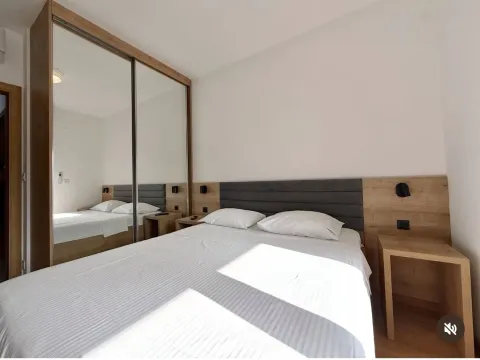 Spavaća soba sa bračnim krevetom, noćnim stočićima i velikim ormarom sa ogledalom. - image 7