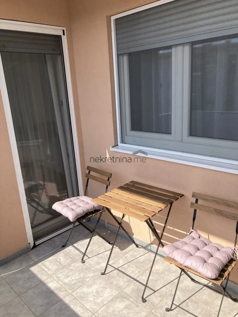 Small balcony with a wooden table and two chairs.
